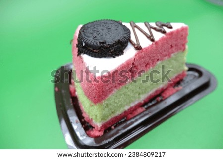 cake pieces with 3 colored layers. cake with biscuit topping and white chocolate. cake isolated on green background.