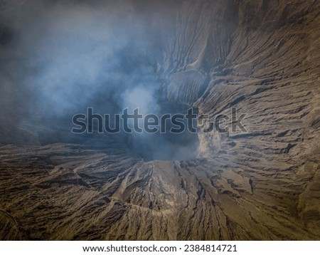 Aerial landscape view of the Bromo volcano crater with smoke coming. An active volcano in Tengger Semeru National Park in East Java, Indonesia. Royalty-Free Stock Photo #2384814721