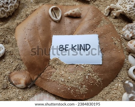 Be kind writing on beach sand background.