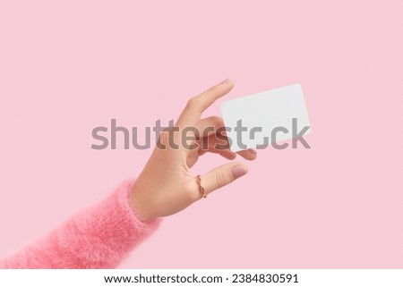 Womans hand touch a white blank business card that floats on a pink background. Flat lay of a simple business card with top view