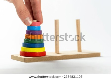 Man solving a tower of Hanoi moving elements with his hand, puzzle recursive algorithm computer science problems abstract, object closeup, toy. Algorithmic problem solving, IT job interview questions Royalty-Free Stock Photo #2384831103