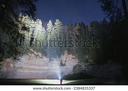 A little girl illuminates a mountain at night with a flashlight, Taevaskoja, photo with weak lighting. High quality photo