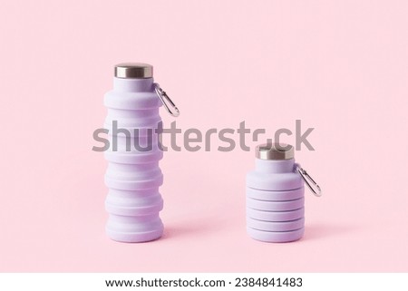 Collapsible reusable lilac water bottle on pink background. Sustainability, eco-friendly lifestyle Royalty-Free Stock Photo #2384841483