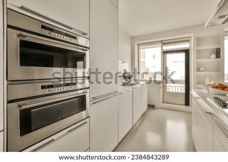 a kitchen with two ovens and an open door leading to the outside space in front of the counter area Royalty-Free Stock Photo #2384843289