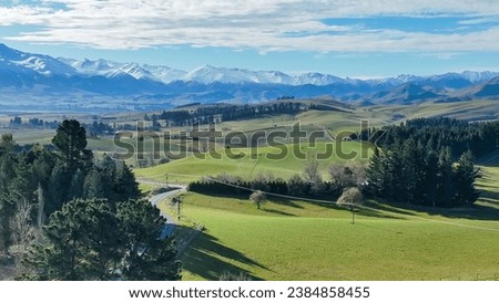 Panoramic  aerial views of mountain ranges and rolling hills and valleys covered in lush green rural agricultural  farming crop and grazing countryside