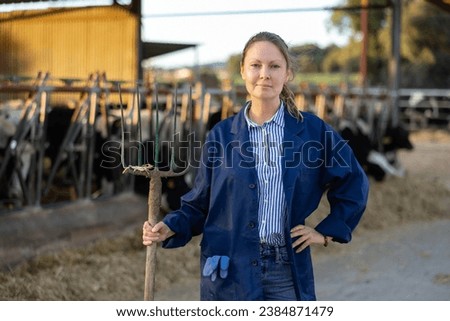 Portrait of female farm owner in a cowshed Royalty-Free Stock Photo #2384871479