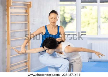 Engaging in training session, women perform elbow blow with wristlock exercises.