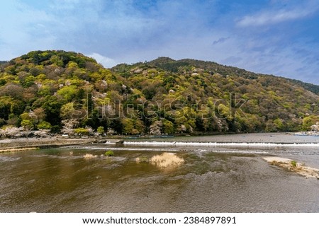 Beautiful stream with small gorge in a blur background of colorful trees on the mountain and the embankment, in spring time under blue sky