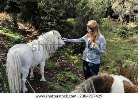 Girl, woman caring for, spending time with a cute pony, a small horse who is standing next to her. Heartwarming petsitting, housesitting experience. Late summer, beginning of autumn in the bush.