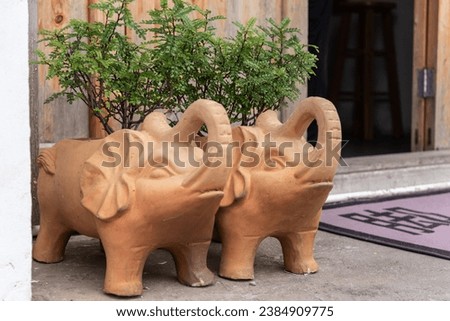 Two elephant cartoon shape redware flowerpots at the door of the house. Ornaments made from pottery.