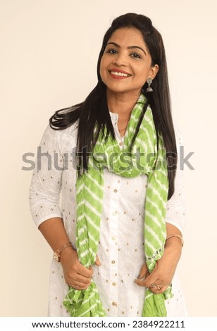Indian happy woman wearing traditional white kurta and green dupatta on studio background