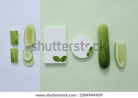 Top view of fresh cucumber slices, mint leaves and white empty podiums decorated on white and green background. Creative background for advertising cosmetic product with blank space for design