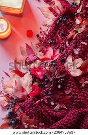 pink autumn background with candles, leaves and knitting