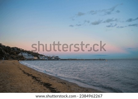 a elegant curve of coastline where the blue sky meets the pink sunset