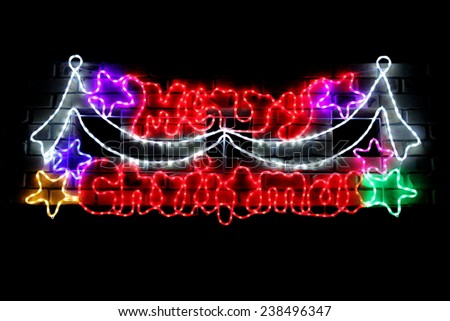 Merry Christmas in lights on brick wall