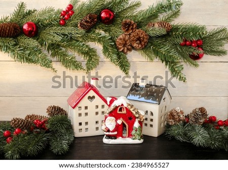 Christmas card on a wooden background. New Year's houses and Santa Claus's house decorated with toys; green fir branches.  Christmas and New Year holiday concept.  Background image front view.