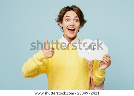 Young woman student wear casual clothes yellow sweater backpack bag hold card sign with IT title text choose job show thumb up isolated on plain blue background. High school university college concept