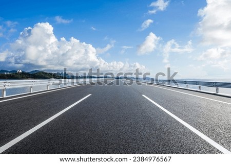 Straight asphalt highway and skyline under blue sky Royalty-Free Stock Photo #2384976567