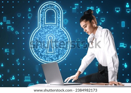Attractive young european businesswoman working at desk with laptop and creative padlock hologram on blue background with various icons. Digital safety and security concept