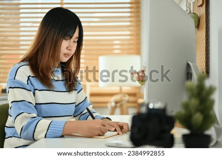 Photo of young woman writing notes checking schedule or planning workday.