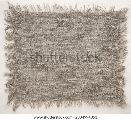 A piece of coarse linen burlap fabric with a raw edge, closeup Royalty-Free Stock Photo #2384994351