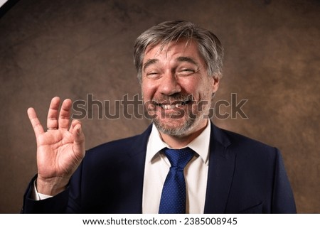 portrait of a 50 year old businessman, company boss or office worker who makes a sign with his hand to show that everything is fine. Sign of success in one's career
