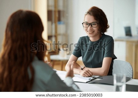 Cheerful HR manager talking to applicant in meeting