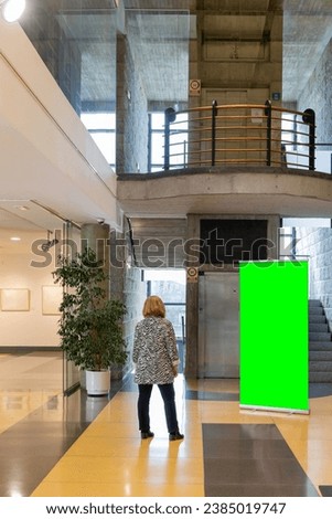 Woman inside a modern building looking at a custom roll up. Banner Mockup