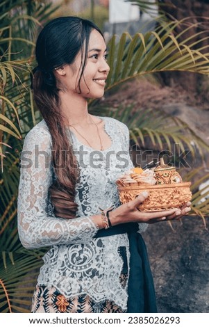 Indonesia Woman with a basket flower offerings a lush green setting - edit mood color