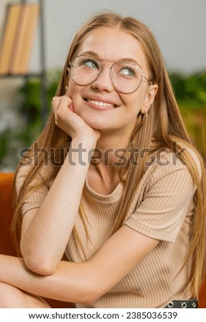 Portrait of happy young woman at home couch smiling friendly, glad expression looking away dreaming resting, relaxation feel satisfied concept good news, celebrate win. Girl on room couch. Vertical Royalty-Free Stock Photo #2385036539
