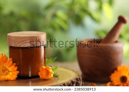 Jar of cosmetic product and beautiful calendula flowers on wooden stump outdoors, space for text