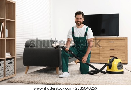 Dry cleaner's employee with vacuum cleaner on carpet in room Royalty-Free Stock Photo #2385048259