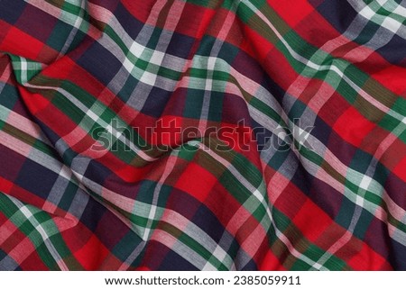 Close-up texture of crumpled red, green and blue tartan fabric. Image for your design. Traditional Scottish clothing Royalty-Free Stock Photo #2385059911