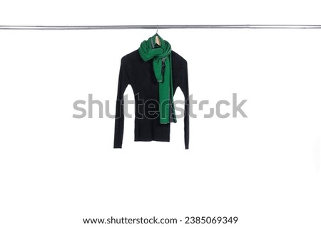 woolen sweater with green scarf hanging on a hanger on a white background
	
