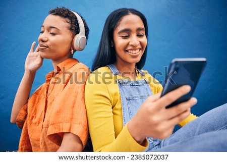 Phone, music and women in city on blue background online for social media, internet and streaming audio. Friendship, happy and female people relax on smartphone listening to song, track and radio