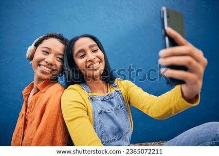 Phone, selfie and women in city on blue background online for social media, internet and profile picture. Friendship, happy and female people relax on smartphone listening to song, track and radio