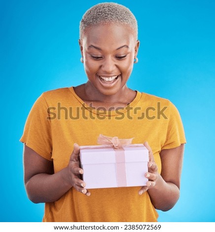 Smile, gift and excited black woman with box in studio isolated on a blue background. Package, happy and African person with present for party, celebration of holiday or birthday for giveaway prize