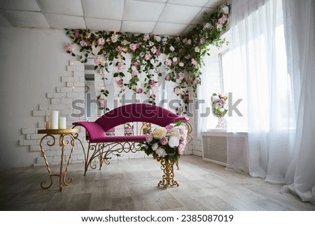 Beautiful interior with a red armchair, couch or sofa and flowers on the front and background. Bright location and a hall for a photo shoot