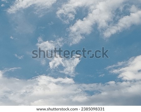 Beautiful blue sky with white fluffy clouds shaped like a standing dog. Close -up shot of the sky.