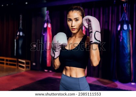 Female Boxer training in Boxing Club. Woman Boxing fighters training at gym. Strong muscular woman practicing box in pink boxing gloves in gym.	