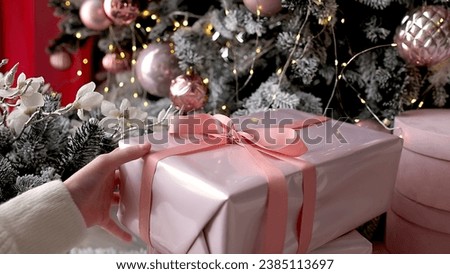 Children's hands touch stylish boxes of Christmas gifts on the background of a decorated Christmas tree. Christmas and New Year decorations