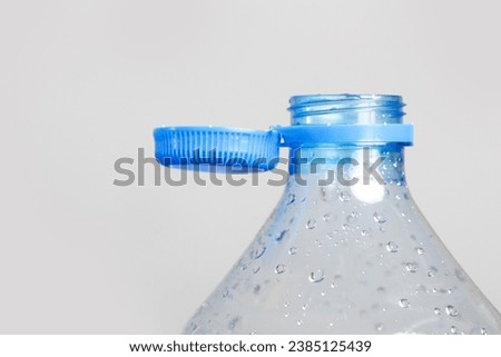 Close up of new cap attached to plastic bottle, connected to the neck of the bottle by solid tab attached to safety ring. They are intended to encourage recycling, as part of the fight against litter. Royalty-Free Stock Photo #2385125439