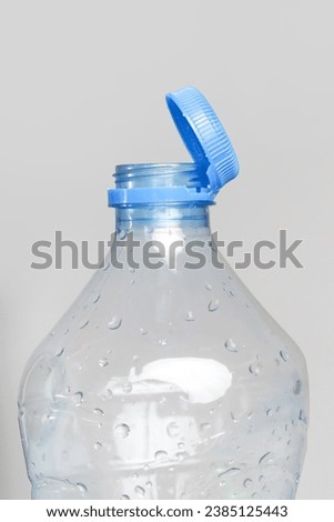 Close up of new cap attached to plastic bottle, connected to the neck of the bottle by solid tab attached to safety ring. They are intended to encourage recycling, as part of the fight against litter. Royalty-Free Stock Photo #2385125443