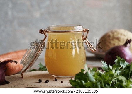 Chicken bone broth or soup in a glass jar with herbs and vegetables