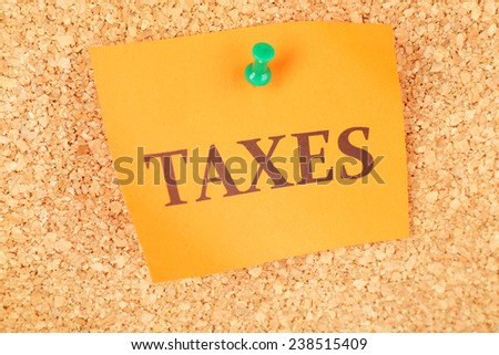 Paper sheet with inscription "Taxes" on wooden background
