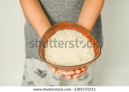 rice in a wooden bowl held by hand, zakat concept