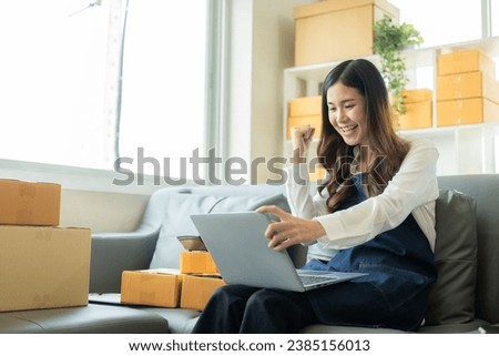 Happy Asian woman receives good news from online name order, SME parcel box and uses smartphone to order online email in SME seller chat box, concept