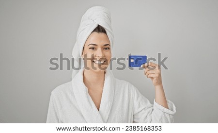 Young beautiful hispanic woman wearing bathrobe holding credit card smiling over isolated white background