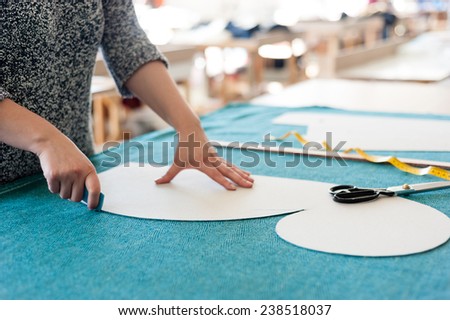 Female fashion designer working with sketches at studio and choosing cloth