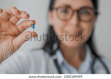Close up of female doctor with stethoscope holding pill in hand. Anti-body, antibiotic, antidepressant, painkiller, oral contraceptive. Pharmacology concept. Side effect of drugs, content prescription Royalty-Free Stock Photo #2385189499